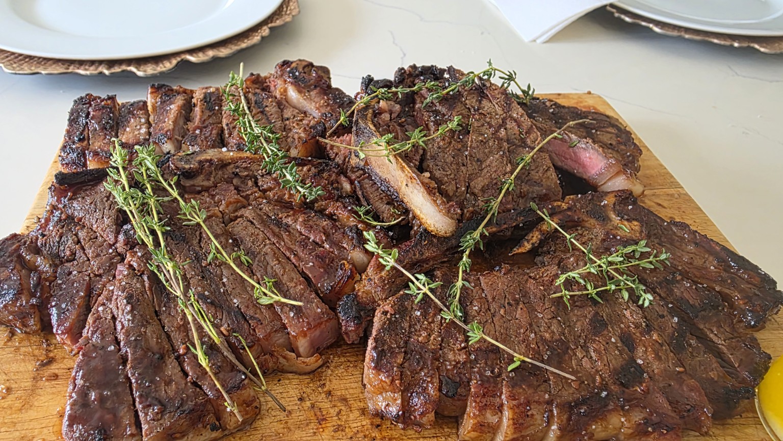 Sliced grilled steak platter with fresh herbs